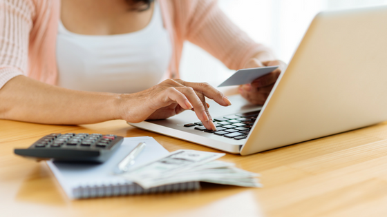 Photo of woman holding credit card and typing in the number on a laptop keyboard