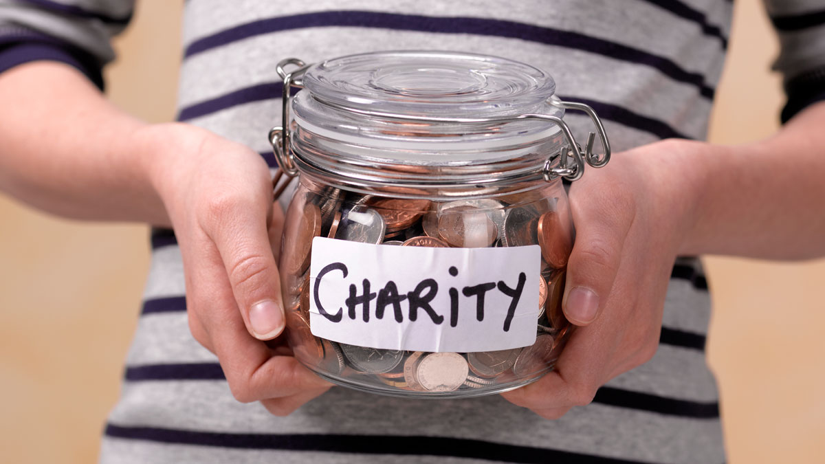 Photo of a person holding a jar with a label that says "Charity" on the front.