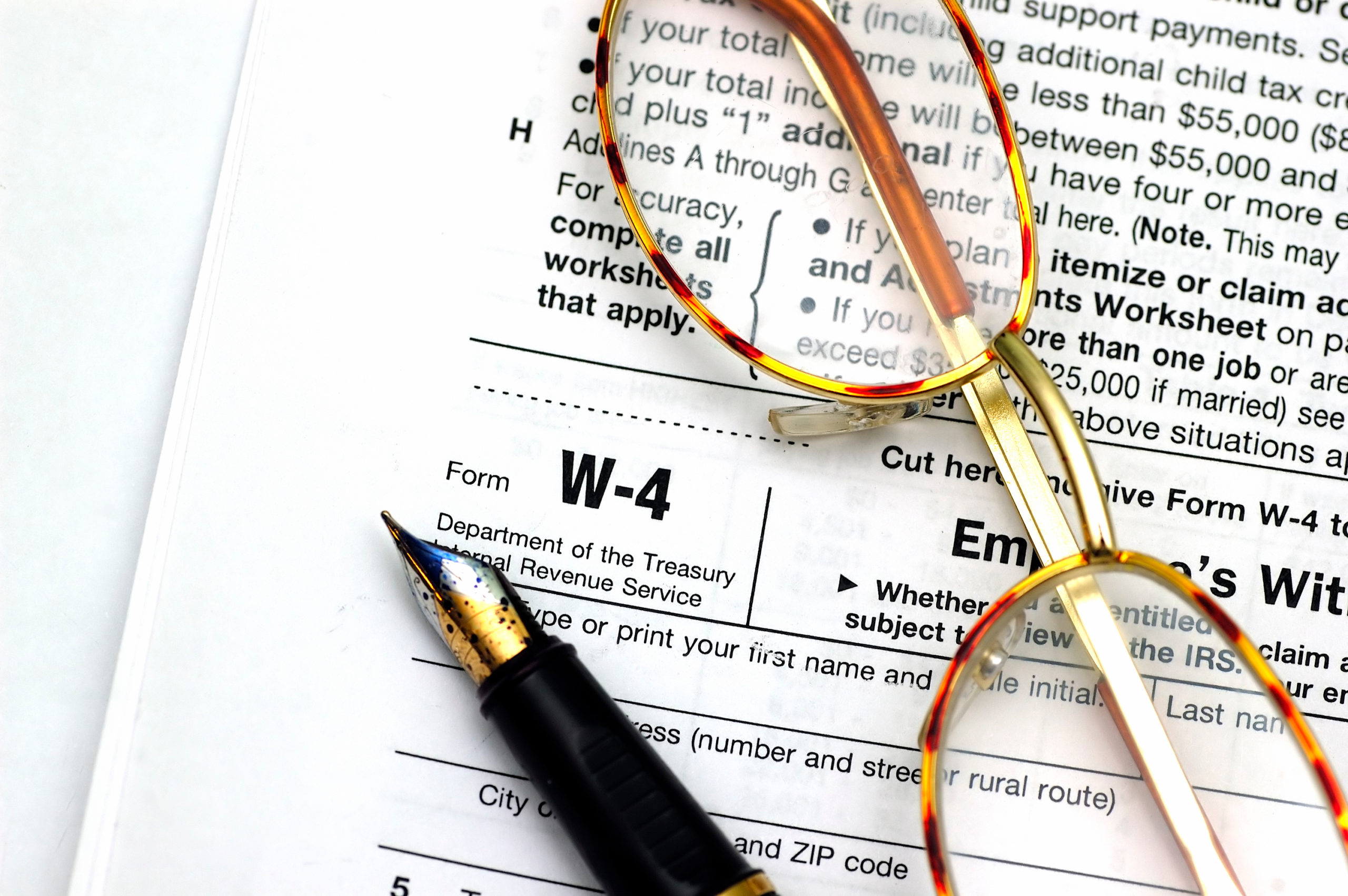W-4 form, with a pen and glasses sitting on top.